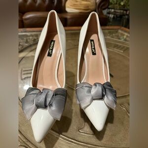 White patent leather pumps with grey sheer bow details.